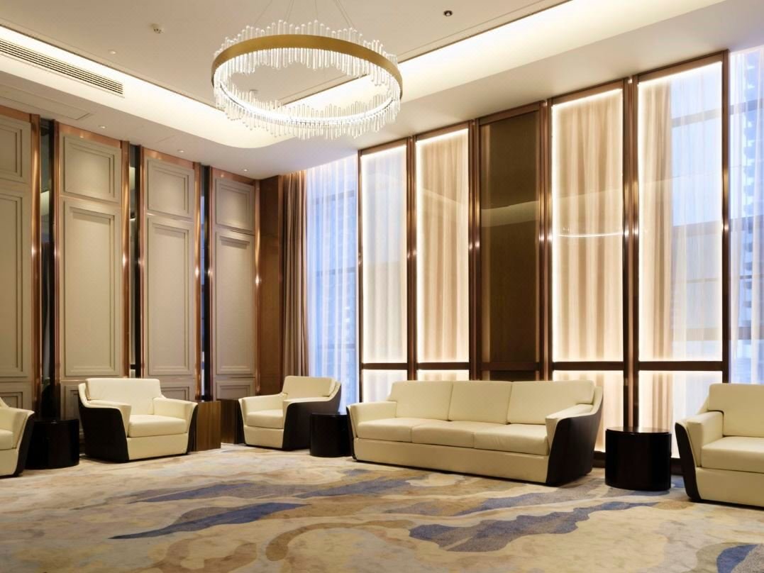 Hotel lobby lounge area with large bronze metal-framed backlit wall panels by XYC Metalworks.