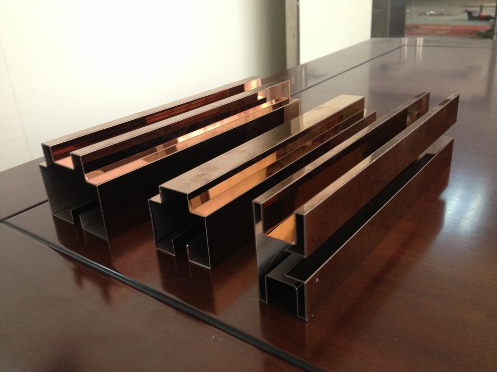 High-mirror PVD stainless steel U-channel profiles in rose gold finish for luxury decor.