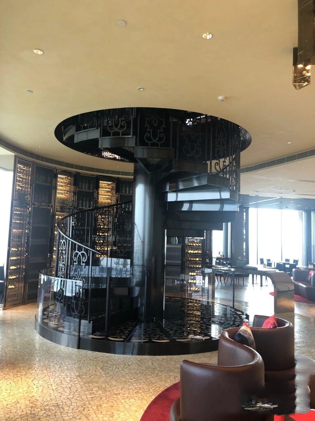 Architectural Stainless Steel Staircase Systems featuring a custom black PVD metal spiral staircase with ornate architectural balustrades for a luxury restaurant interior.