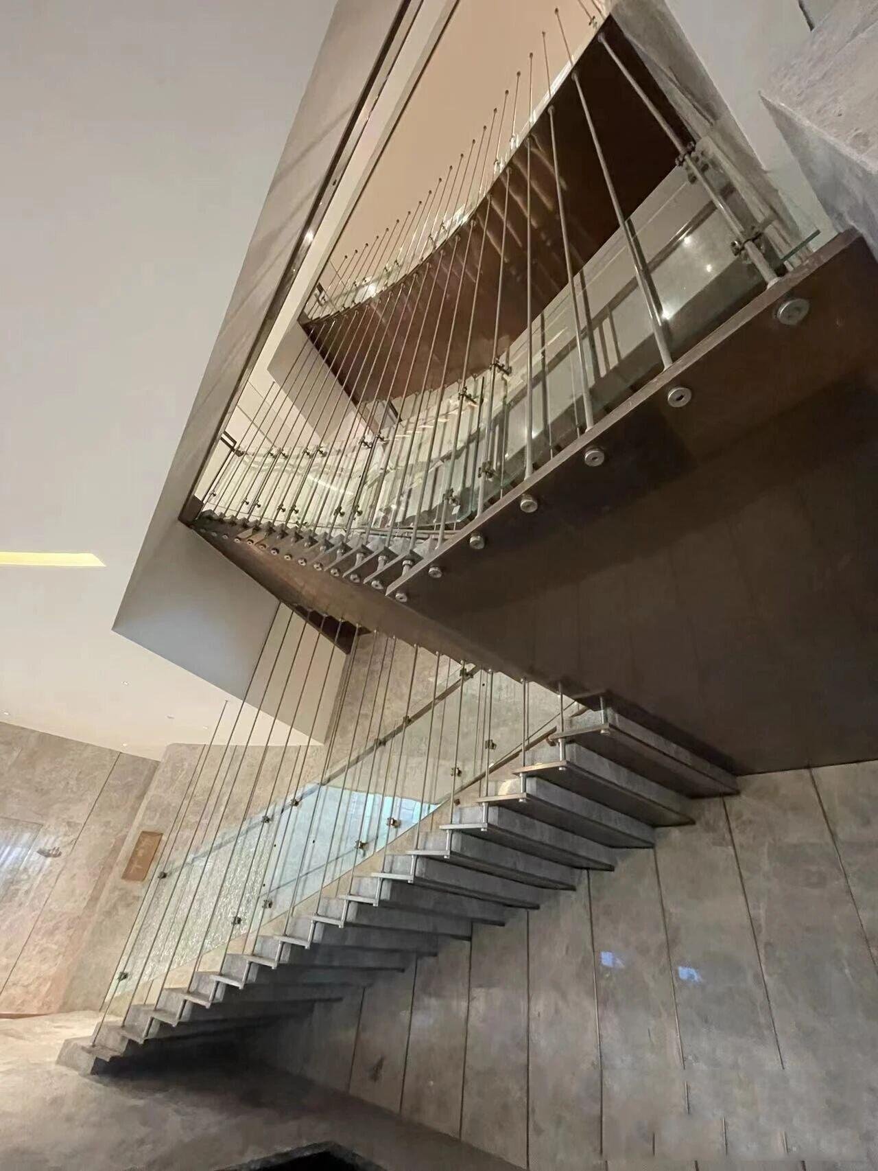Modern floating cantilevered Architectural Metal Staircase with stone treads and vertical tension rod Stainless Steel Balustrade Systems.