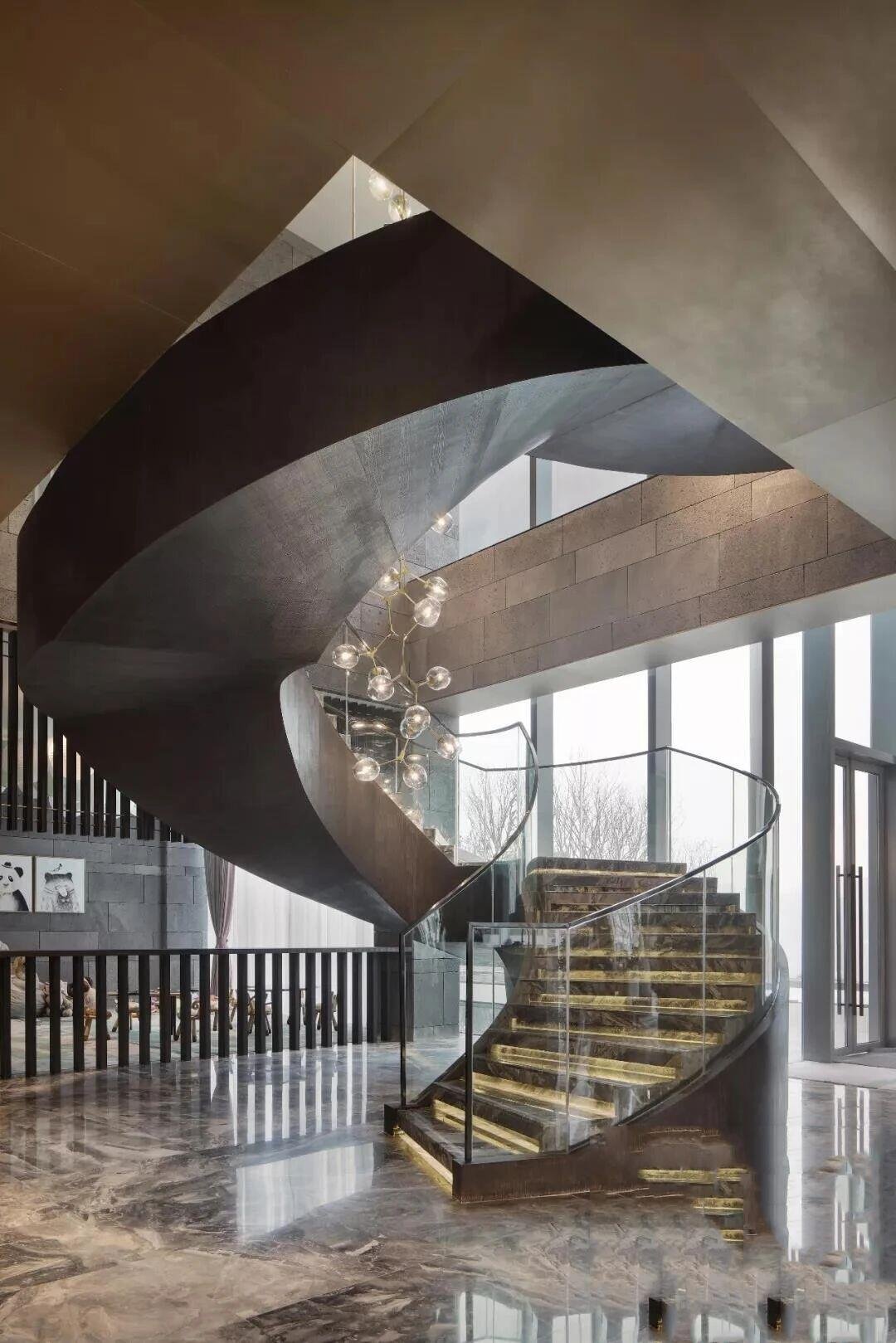 Architectural Stainless Steel Staircase Systems in a helical curved design featuring a custom metal ribbon stringer and LED illuminated stone treads for luxury architectural interiors.