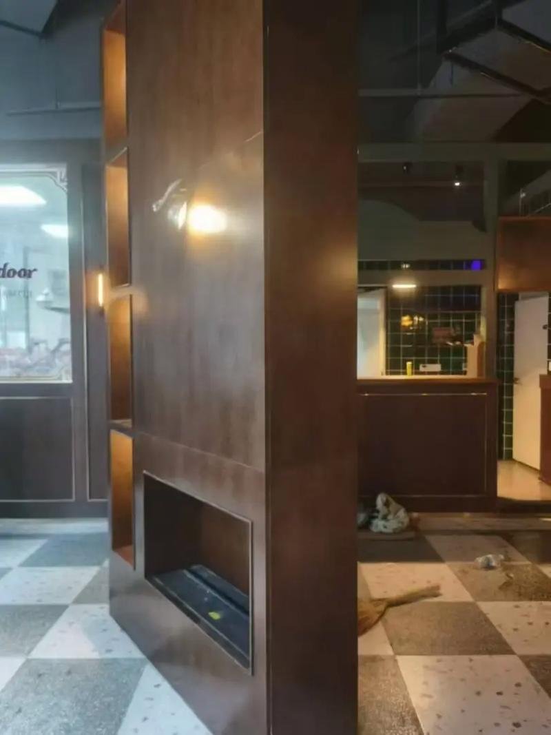 Architectural aged bronze cladding used for a large interior feature wall and fireplace surround in a luxury commercial space.