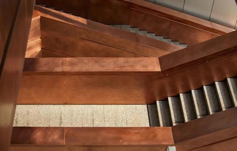 Custom aged bronze cladding for an architectural staircase by XYC Metalworks, providing a timeless aesthetic for luxury interiors.