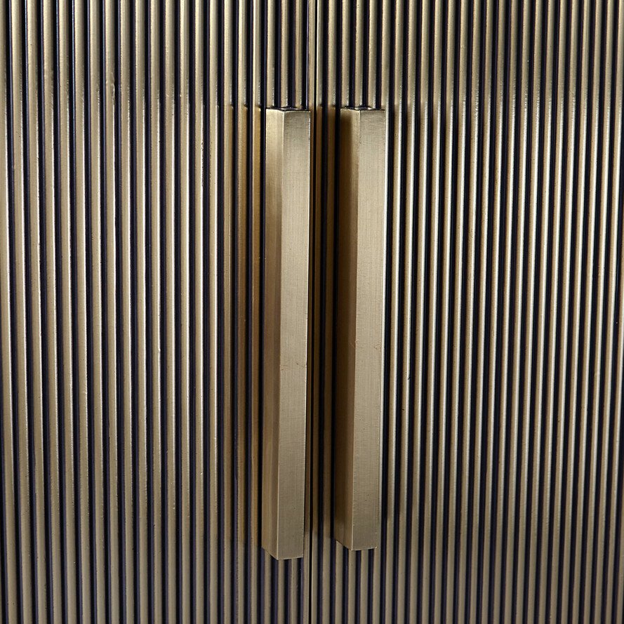 Brushed brass hexagonal door handles made from antimicrobial copper alloys on fluted bronze cabinetry.