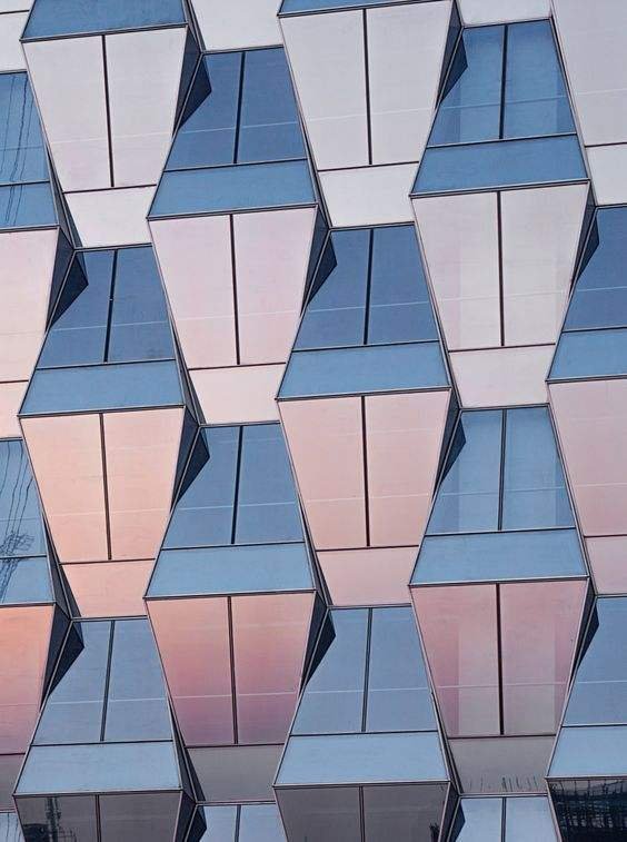 Modern geometric glass facade supported by a premium architectural aluminum solutions framing system.