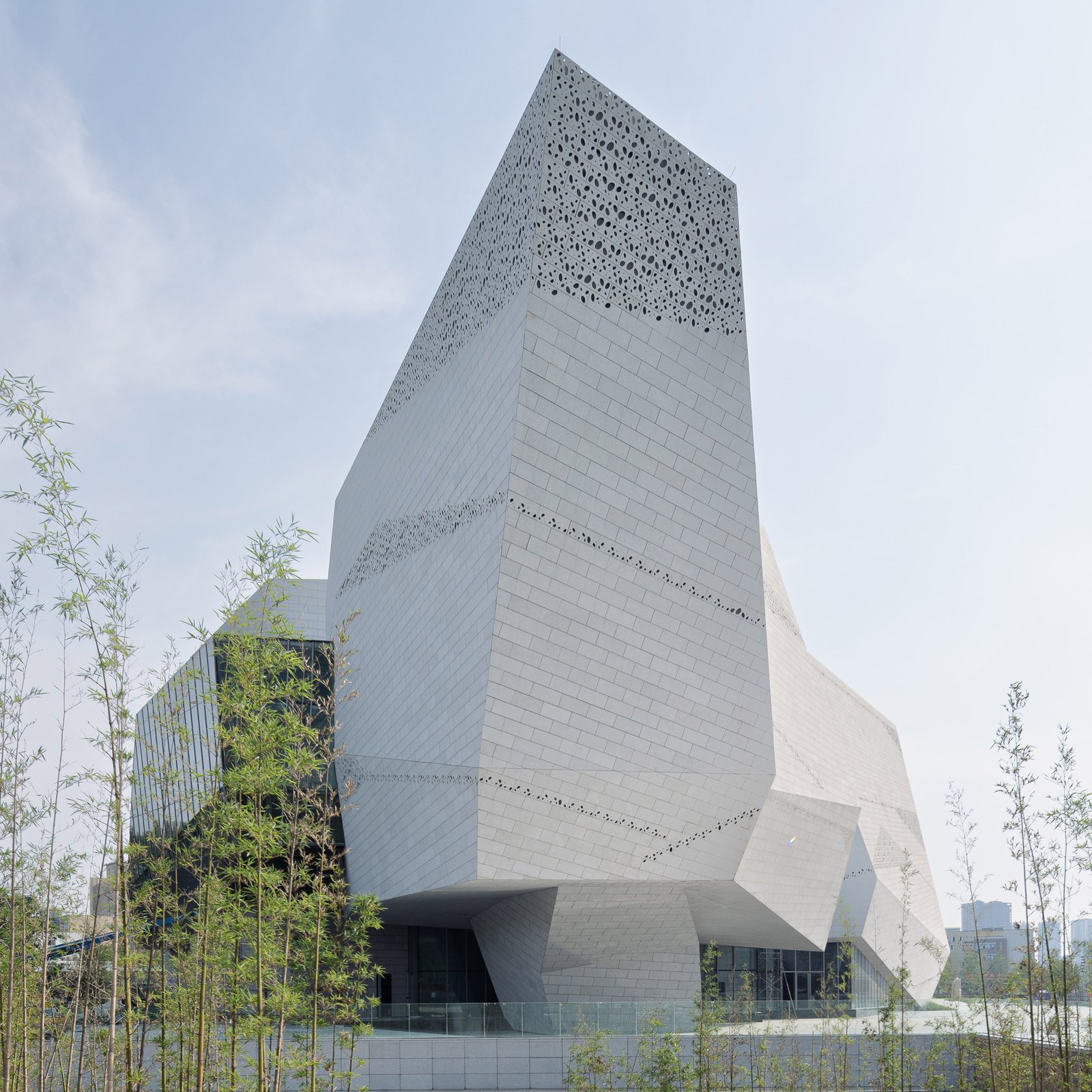 Iconic museum architecture utilizing perforated stainless steel sheets for complex geometric facades and natural light diffusion.