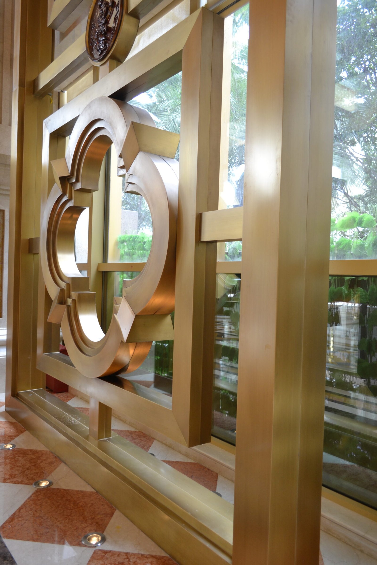 Architectural Metal Partitions with bespoke laser-cut geometric patterns and a reflective PVD gold finish for interior luxury.