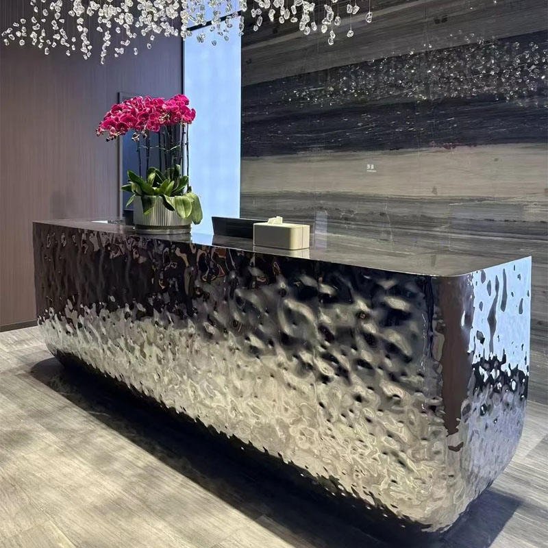 Bespoke mirror-polish hammered stainless steel reception desk for a luxury hotel lobby or concierge station.