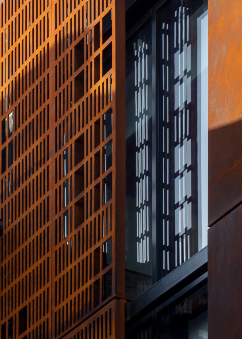 Bespoke perforated Corten steel sunshade screen providing architectural texture and solar control for a modern facade.