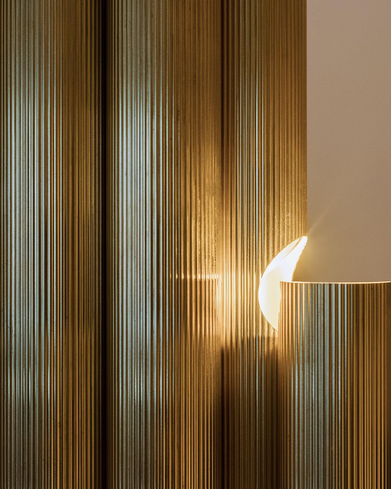 Close-up texture of fluted wall panels utilizing high-quality brass alloy grades c260 & c280 with custom lighting.