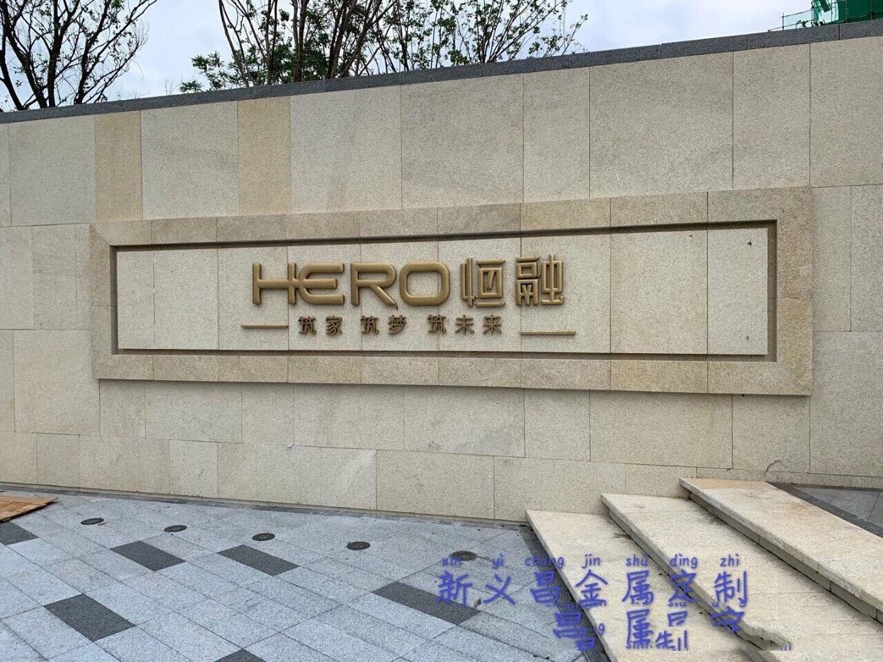 Exterior architectural metal signage featuring bronze dimensional letters for corporate branding on a luxury building facade.