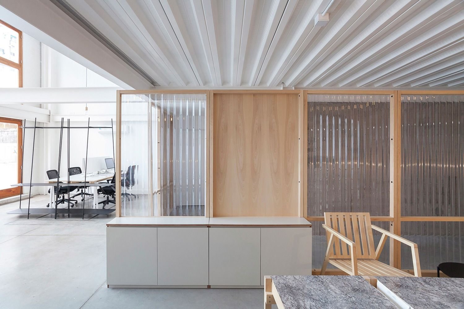 Bright office interior featuring corrugated metal sheet ceiling panels and custom architectural partitions by XYC Metalworks