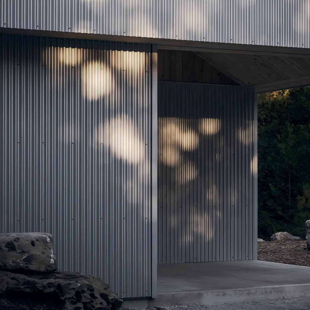 Architectural building exterior showcasing corrugated stainless steel roofing and facade cladding with creative night lighting.