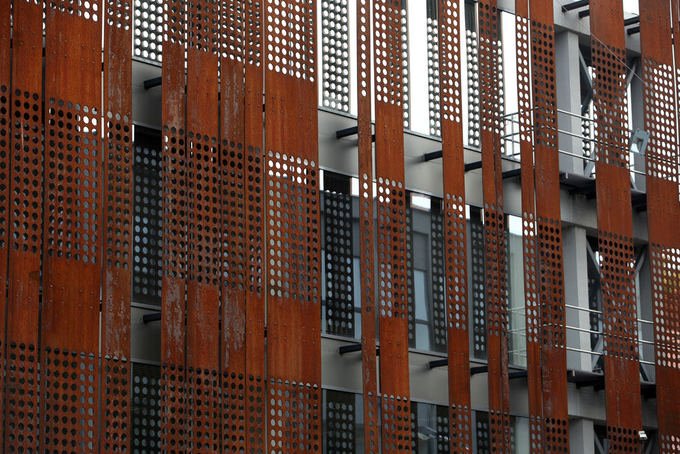 Vertical perforated fins used in a large-scale Corten steel architectural facade project.