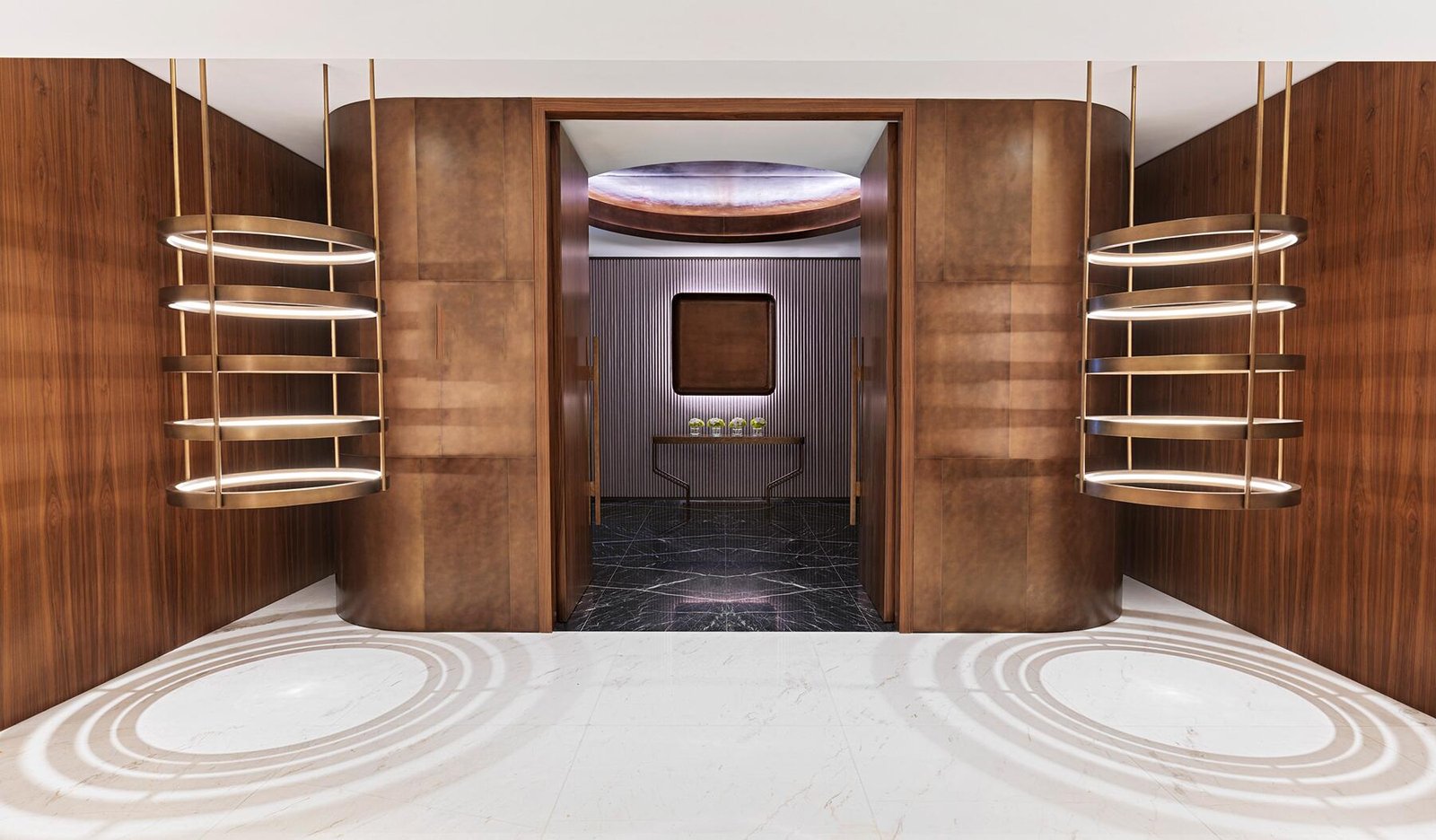 Luxury hotel suite entrance featuring antique custom architectural brass & bronze curved wall panels.