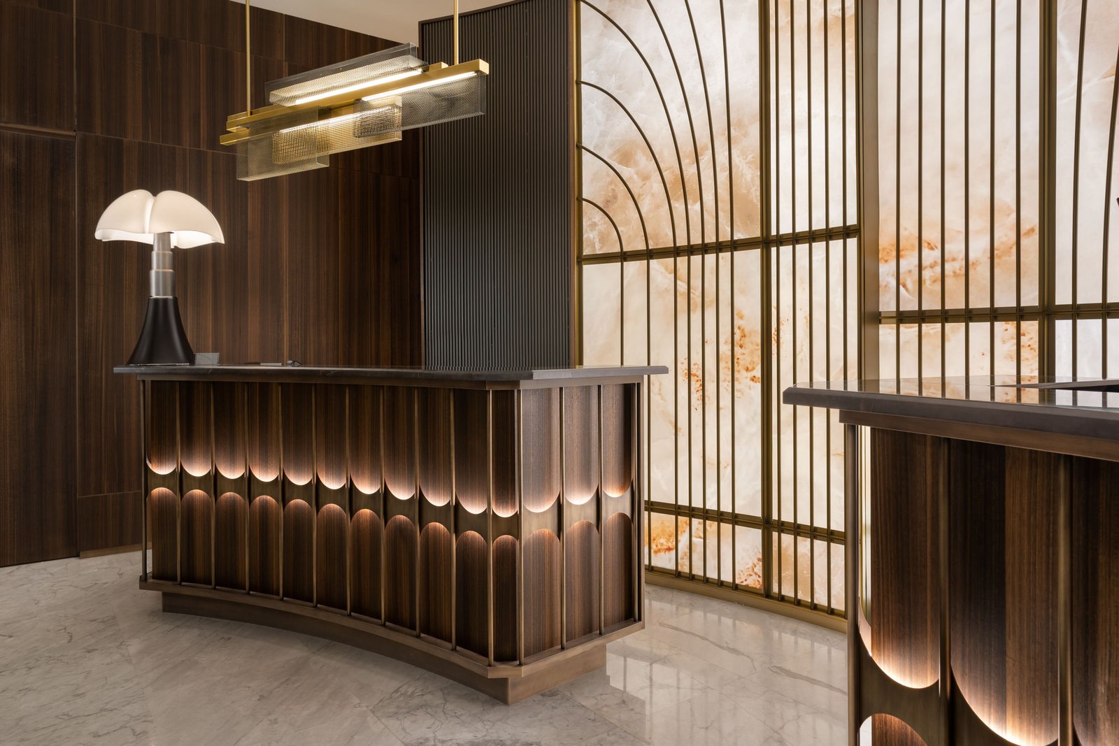 Bespoke curved and scalloped bronze reception desk highlighting premium custom architectural brass & bronze design.