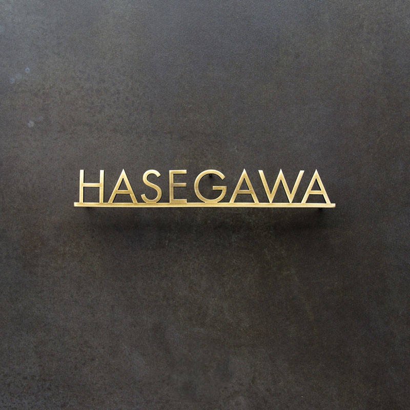 Custom fabricated brass 3D letters for Hasegawa restaurant branding, featuring a premium brushed satin finish.
