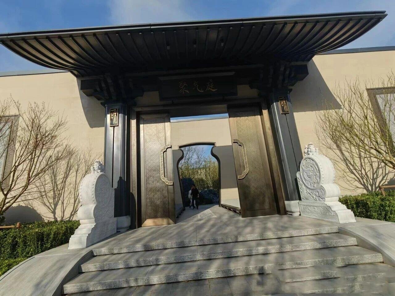 A unique, custom-fabricated curved metal gate in a Chinese style, finished in antique bronze with intricate handles