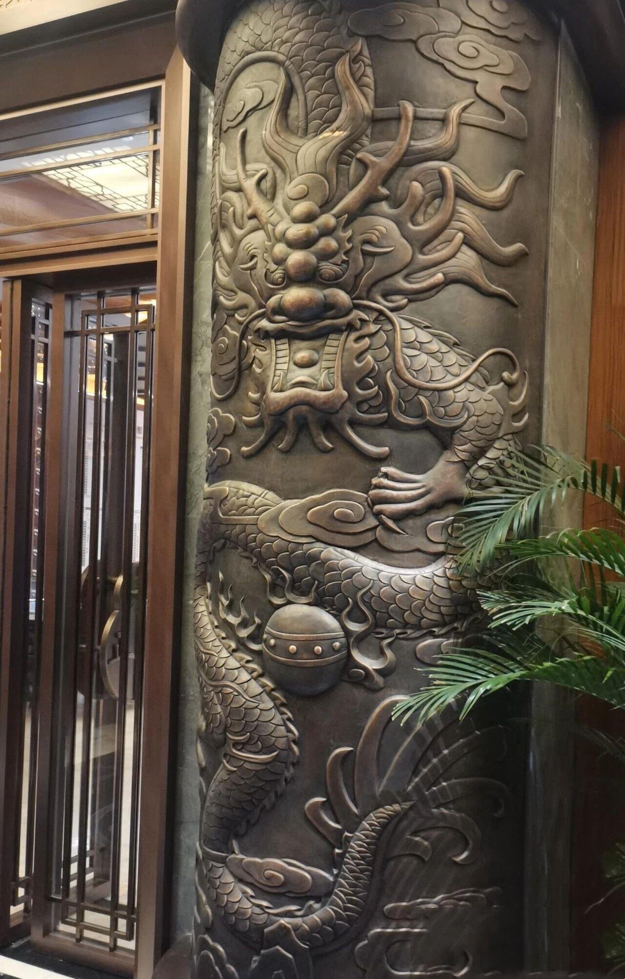 Stainless Steel Column Covers featuring a bespoke metal relief with a traditional Chinese Dragon motif for luxury architectural interiors