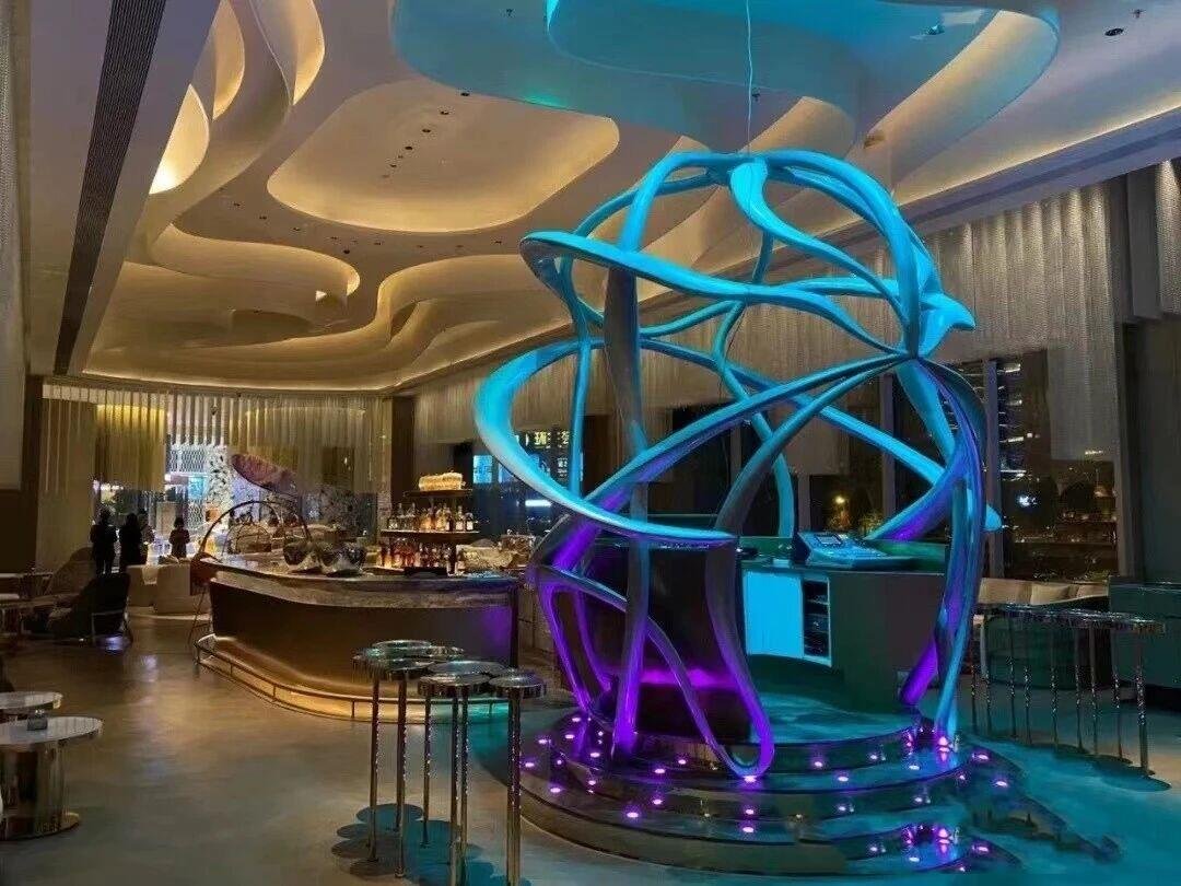 Futuristic custom-fabricated curved metal sculpture bar with blue LED lighting for luxury lounge interior by XYC Metalworks.