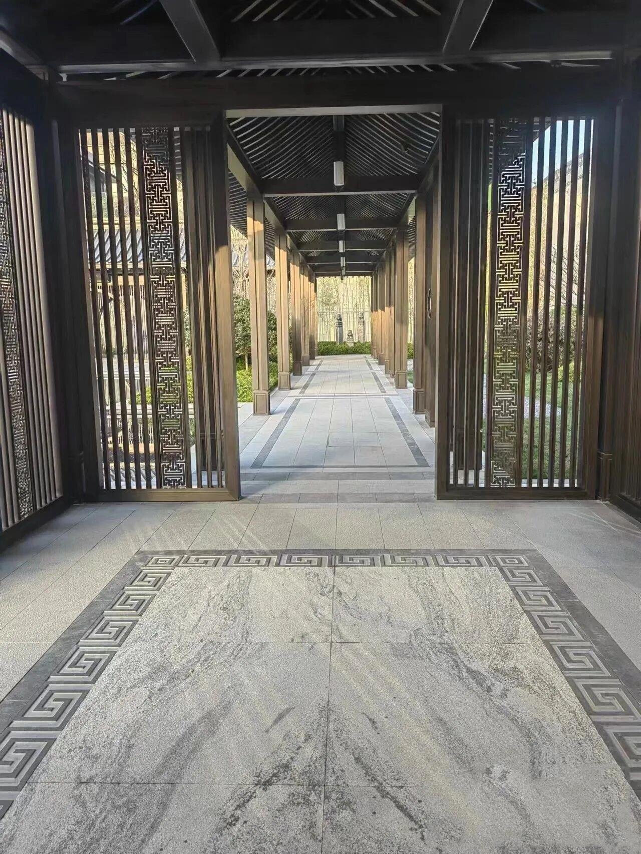 A pergola walkway fabricated from hairline brushed, PVD coated bronze color stainless steel, featuring a louvered roof and decorative louvered side screens