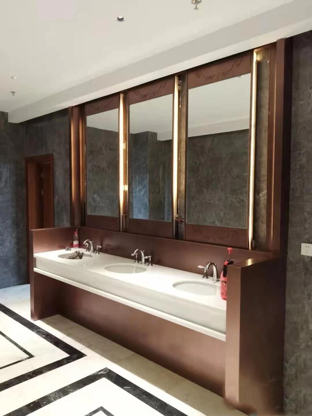 Integrated luxury vanity station featuring a PVD bronze frame, three backlit mirrors, and a stone countertop.