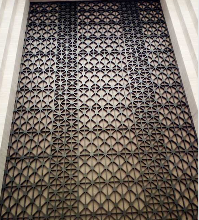 Large-scale architectural facade cladding featuring laser-cut stainless steel sheets with an intricate geometric lattice pattern by XYC Metalworks.