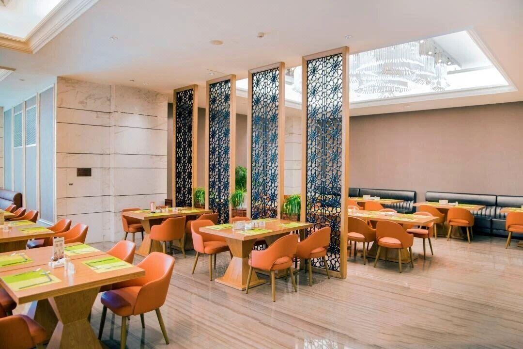 Dark-finished laser-cut stainless steel sheets with intricate organic branch patterns used as decorative restaurant partition panels.