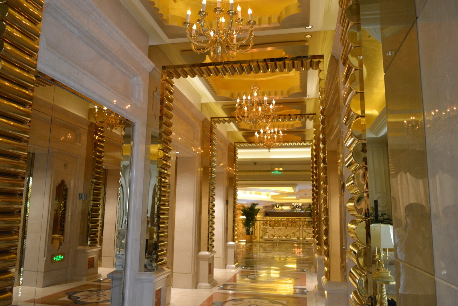 Mirror-polished stainless steel sheets in titanium gold used for monumental column cladding in a luxury hotel lobby.