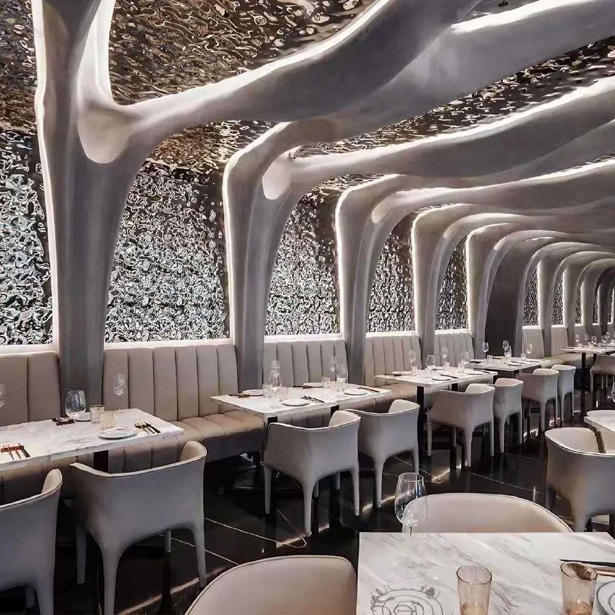 Luxury restaurant interior with an organic architectural theme featuring a polished water ripple stainless steel sheets ceiling.