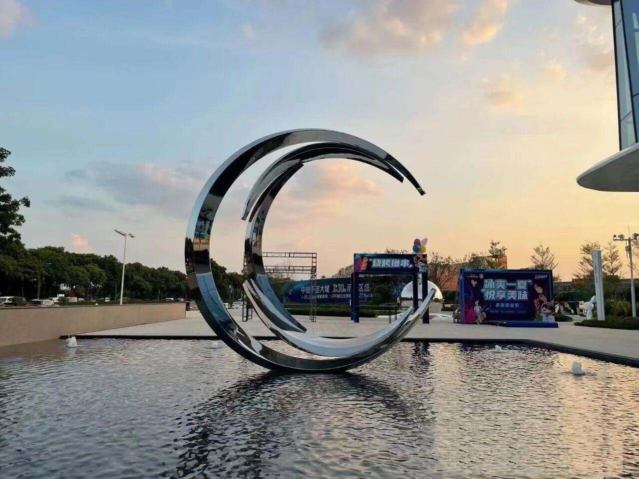 Mirror-polished stainless steel sheets fabricated into a large crescent moon sculpture for luxury outdoor water features.