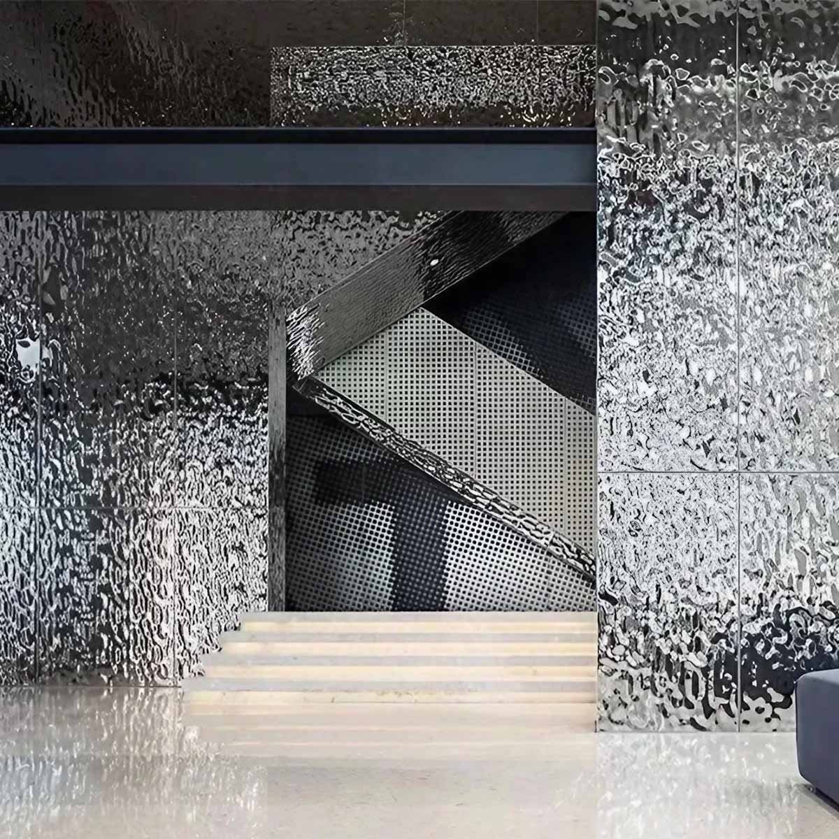 Mirror polished water ripple stainless steel sheets used for dynamic wall cladding in a modern interior lobby by XYC Metalworks.