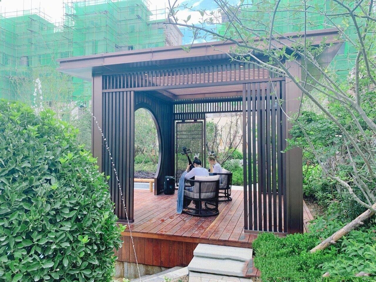 Modern metal louvered gazebo featuring a moon gate and integrated seating area for a luxury residential landscape.
