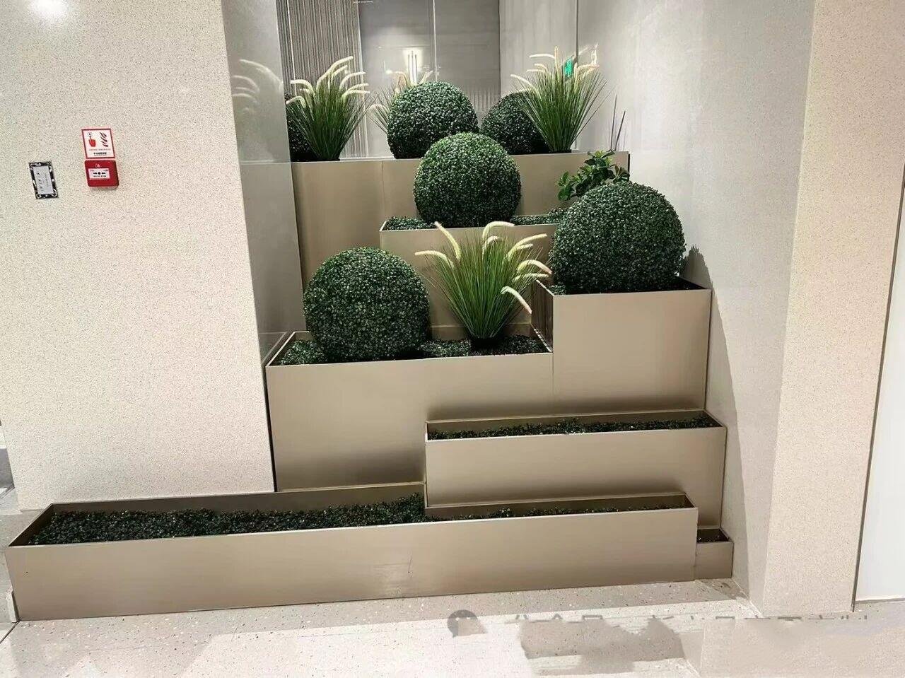 Custom multi-tiered stainless steel planter box in a PVD champagne gold finish for luxury hotel lobbies and terraces.