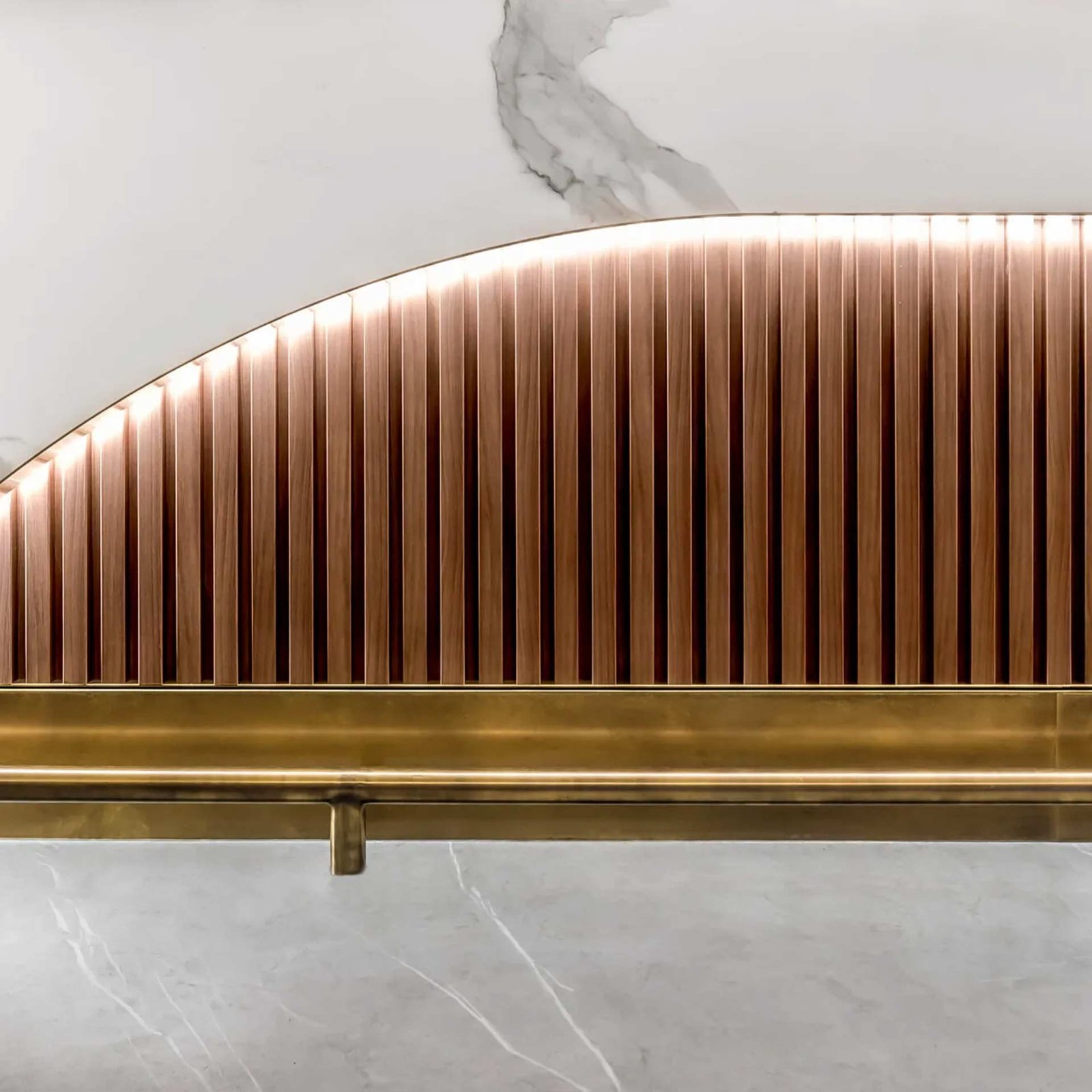 Polished brass handrail profile installed over fluted panels, part of a custom architectural brass & bronze project.