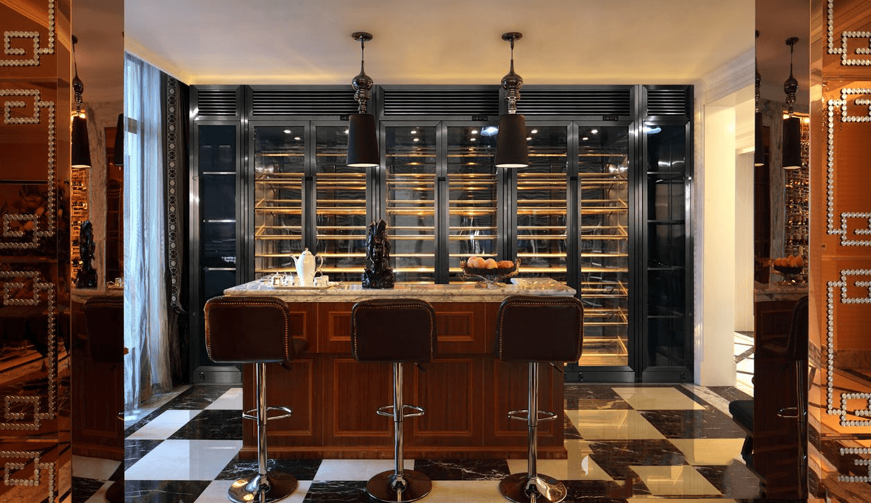 Custom hospitality bar solution featuring a full-wall PVD black stainless steel wine refrigerator system with integrated linear LED lighting.