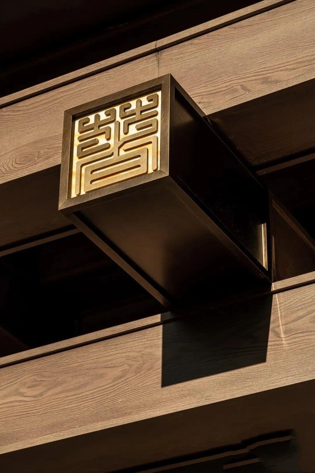 Bespoke architectural metalwork featuring a PVD bronze beam end cap with an integrated laser-cut PVD gold Chinese seal logo.
