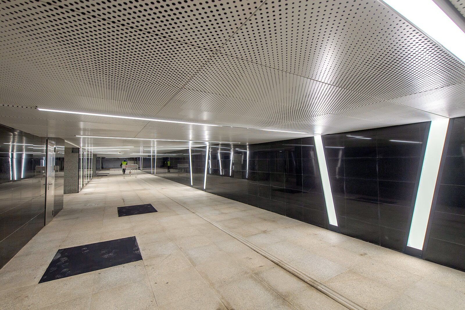 Standard round-hole perforated stainless steel sheets used for acoustic ceiling panels in public stations and commercial lobbies.