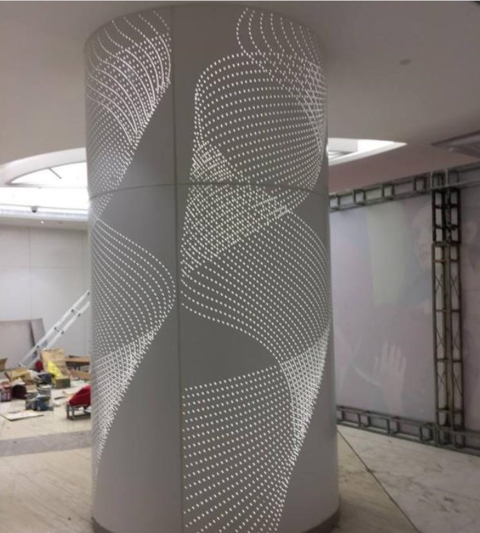Sandblasted stainless steel sheets with custom perforations and integrated backlighting for a modern, low-glare architectural column feature.