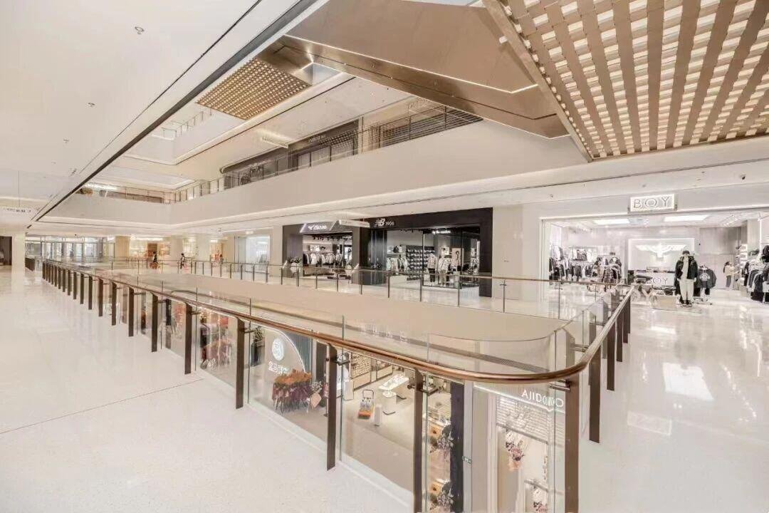 Commercial-grade glass balustrade with a metal top rail installed in a high-traffic retail shopping mall environment.