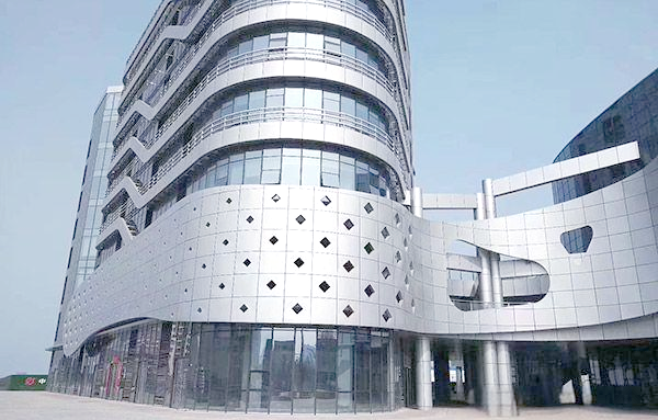 Unique silver architectural aluminium cladding with decorative diamond cutouts on a modern building facade.