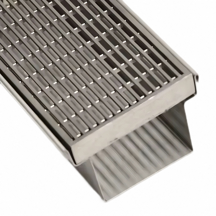 Close-up of a stainless steel press-locked grating cover with a perforated and slotted design, integrated into a custom drainage channel.