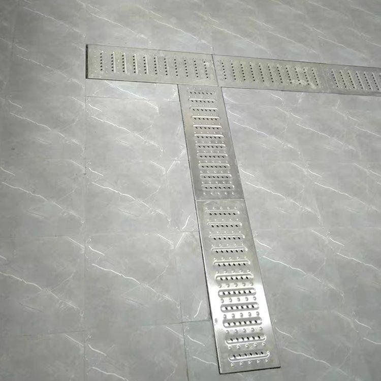 Custom T-junction layout of perforated metal grating plates designed for non-slip industrial flooring.