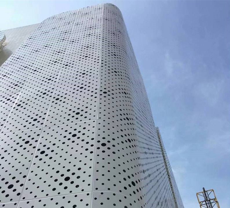 Corner view of a building featuring white perforated architectural aluminium cladding with a durable PVDF finish.