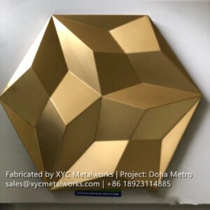 Individual sample of a gold-anodized 3D geometric metal panel, precision-stamped for the Doha Metro project.