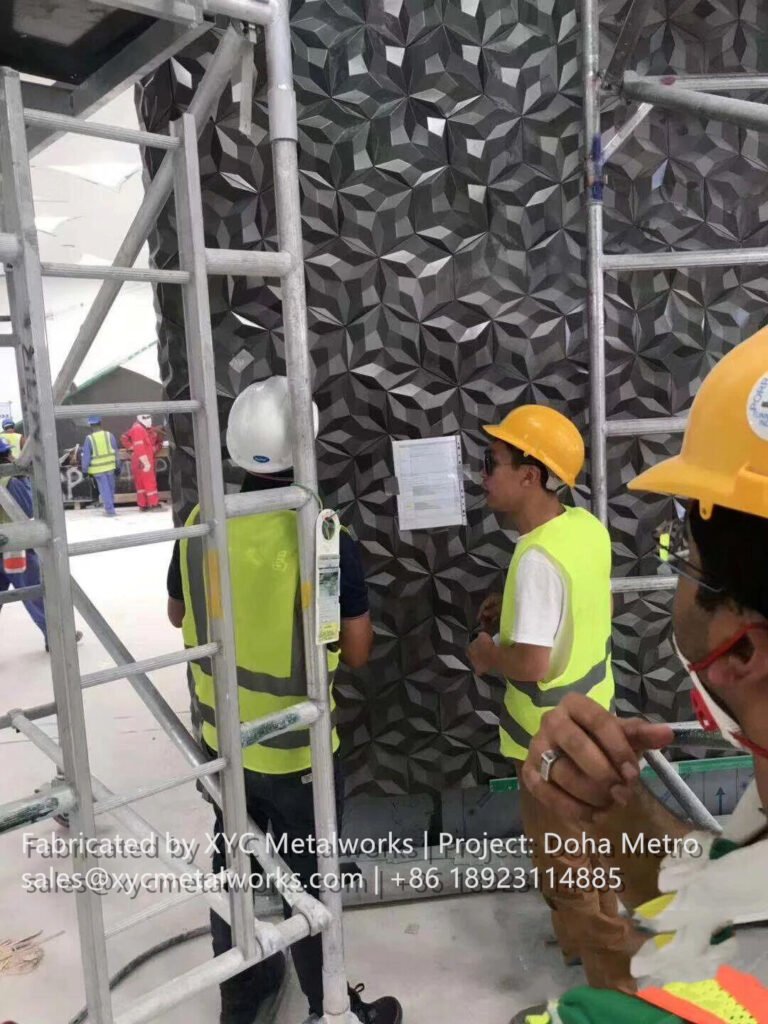 Professional inspection of 3D decorative metal wall panels during installation at the Doha Metro project site by XYC METALWORKS.
