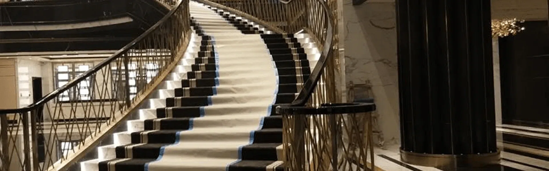Grand hotel lobby staircase featuring a luxury ornate gold-finished architectural metal balustrade.