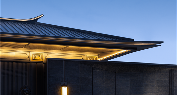 Detail shot of ornamental gold metal trim with traditional patterns integrated into a modern dark metal architectural structure.