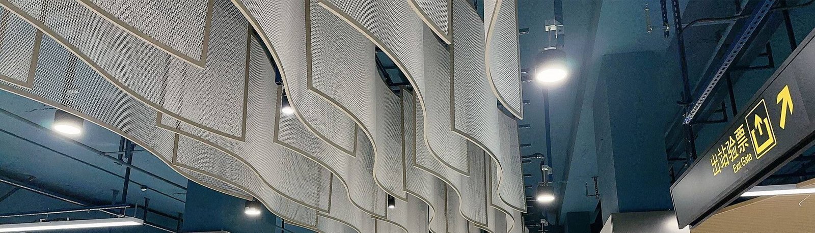 Wavy suspended ceiling system made from architectural expanded metal mesh panels for commercial interiors.