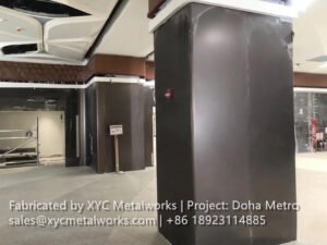 Smooth, dark bronze-finish metal column cladding by XYC Metalworks installed in a main concourse of the Doha Metro station.